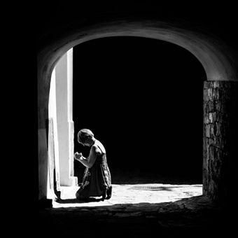 women kneeling and praying, seen through a stone doorway