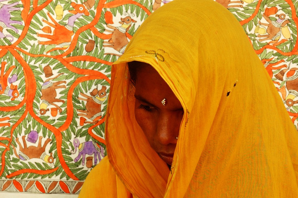 Indian worman looking down, wrapped in a golden shawl